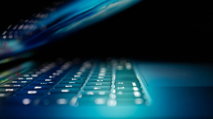 Clavier d'ordinateur portable illuminé en bleu dans l'obscurité.