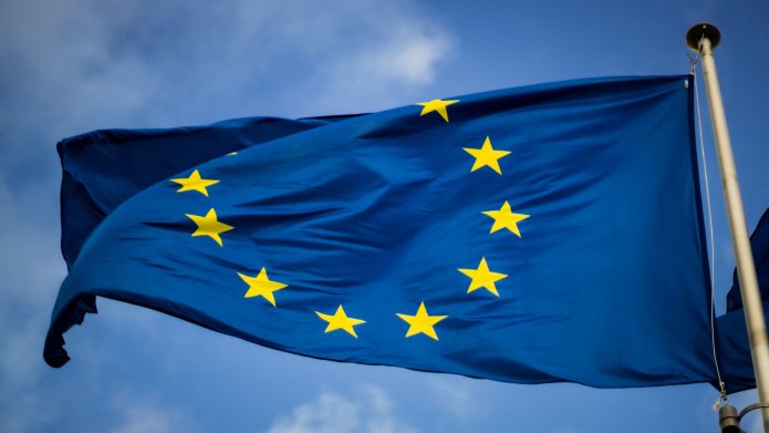 Drapeau de l'Union européenne bleu avec étoiles dorées, flottant au vent.
