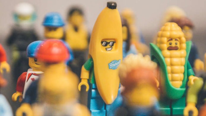 Un personnage lego banane et un personnage lego maïs, entourés de personnages lego ouvriers