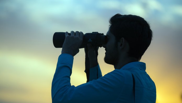 Profile photo of a man with a pair of binoculars