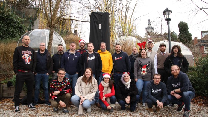 Groupe de personnes souriantes posant devant un monument en plein air, en hiver.
