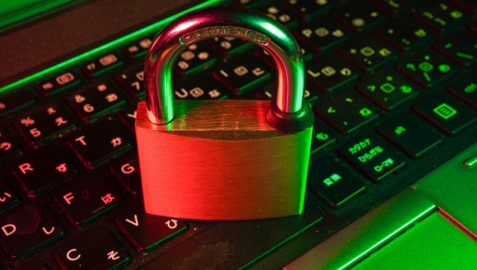 Cadenas métallique rouge posé sur un clavier d'ordinateur éclairé en vert, symbolisant la cybersécurité.