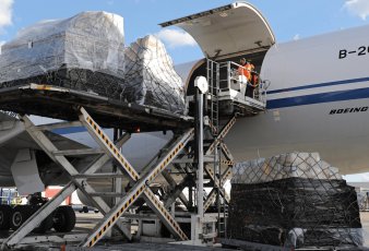 Chargement de marchandises sur palette dans la soute d'un avion cargo sur le tarmac.