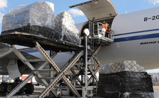 Chargement de marchandises sur palette dans la soute d'un avion cargo sur le tarmac.