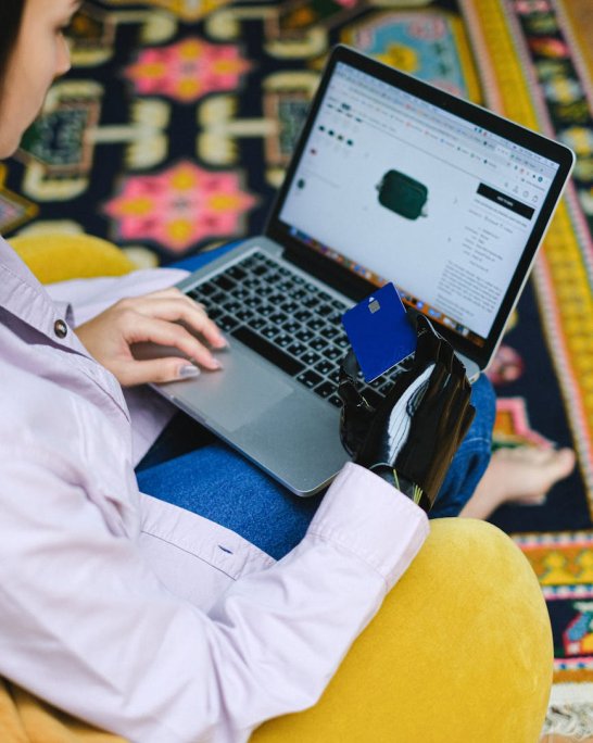 Personne faisant un achat en ligne sur un ordinateur portable avec une carte bancaire en main.