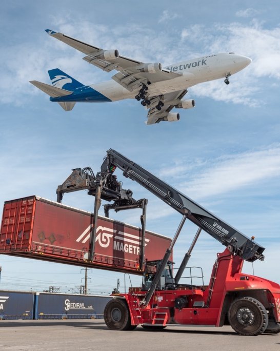 Chariot élévateur rouge manipulant un conteneur rouge, avec un avion cargo en vol au-dessus.